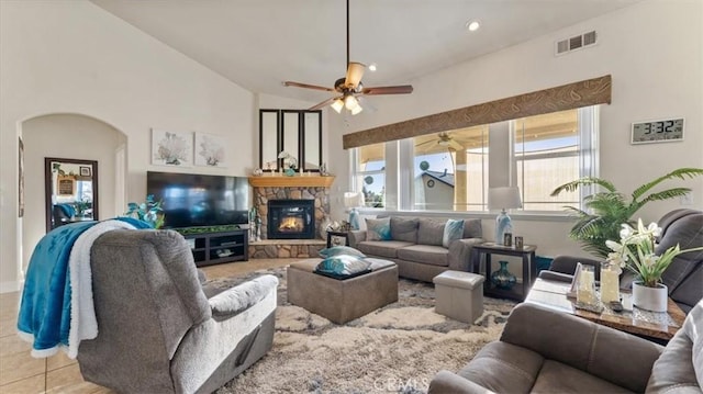 living area featuring arched walkways, light tile patterned floors, a fireplace, visible vents, and a ceiling fan