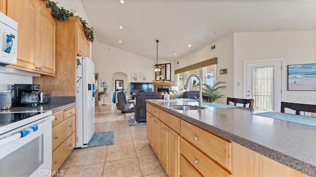 kitchen with white appliances, a warm lit fireplace, open floor plan, light brown cabinets, and a sink