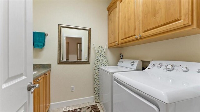 washroom with baseboards, cabinet space, and washing machine and clothes dryer