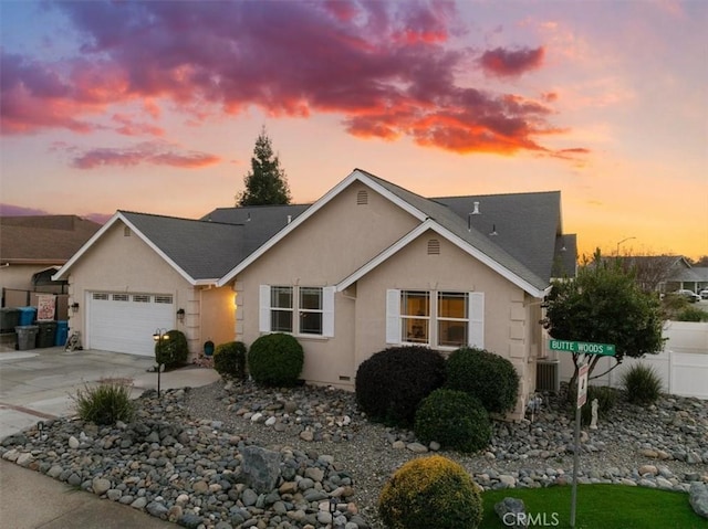 view of front facade featuring a garage, concrete driveway, fence, and stucco siding