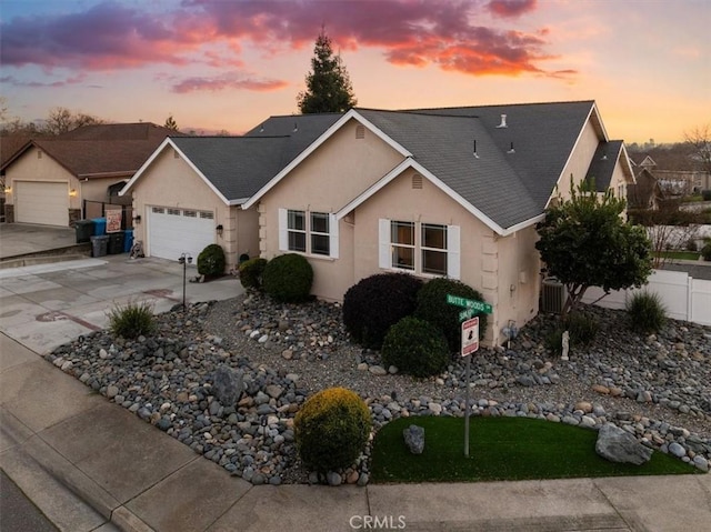 ranch-style home with driveway, roof with shingles, an attached garage, and stucco siding