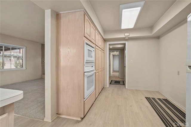 kitchen with light hardwood / wood-style flooring, light brown cabinets, and white appliances