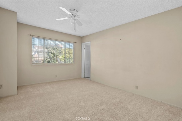 spare room with ceiling fan, a textured ceiling, and light carpet