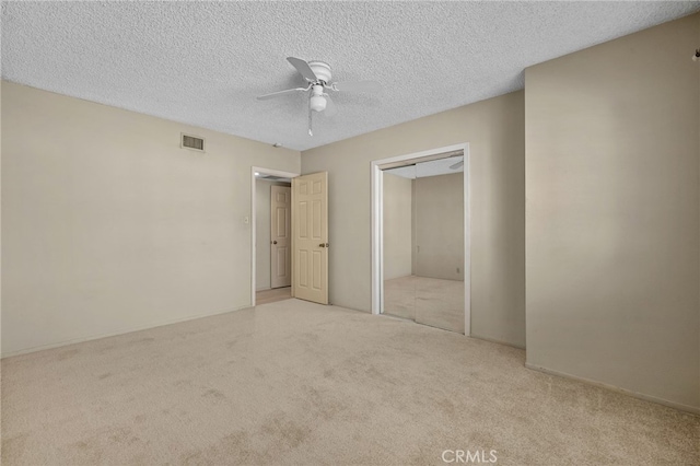 unfurnished bedroom featuring a textured ceiling, ceiling fan, a closet, and light carpet