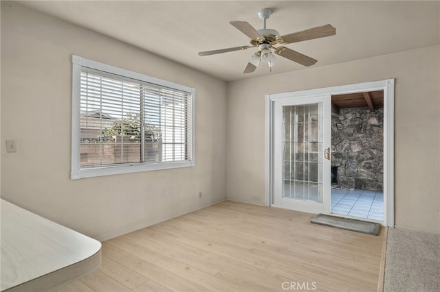 unfurnished room featuring ceiling fan, a fireplace, and light hardwood / wood-style floors