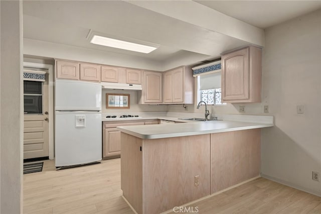 kitchen with light brown cabinets, sink, kitchen peninsula, and white appliances