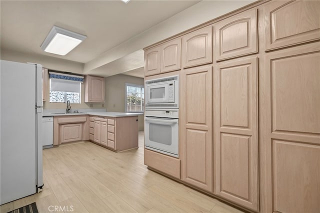 kitchen featuring kitchen peninsula, light brown cabinets, white appliances, light hardwood / wood-style flooring, and sink