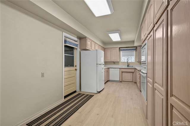 kitchen with light brown cabinetry, sink, white appliances, and light hardwood / wood-style floors