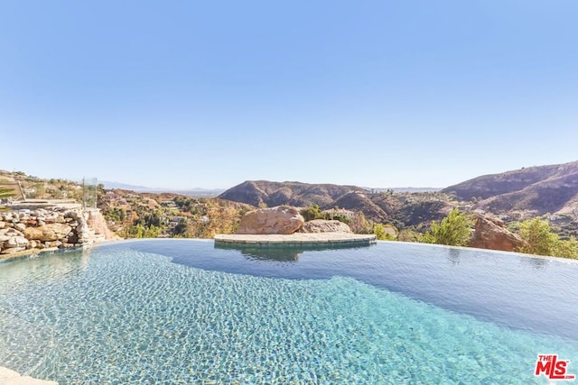 view of swimming pool featuring a water and mountain view