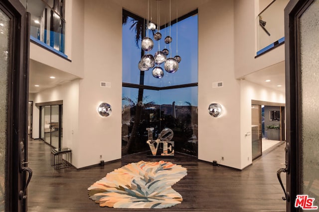 interior space featuring a towering ceiling and dark hardwood / wood-style floors