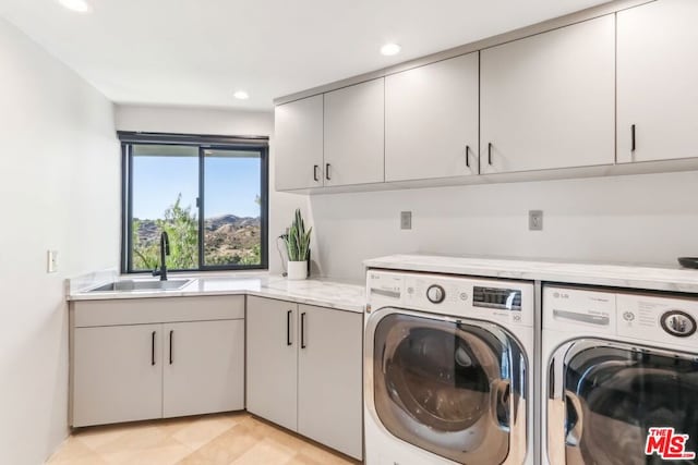 laundry area with cabinets, light tile patterned floors, washing machine and clothes dryer, and sink