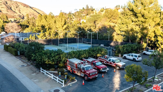 view of parking / parking lot featuring tennis court and a mountain view