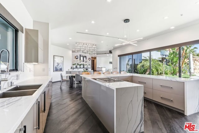 kitchen with dark wood-type flooring, stainless steel gas cooktop, pendant lighting, and a spacious island