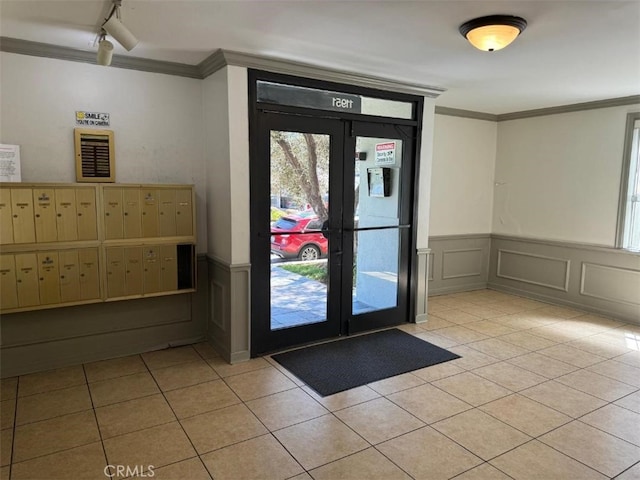 doorway to outside with crown molding, light tile patterned floors, and rail lighting