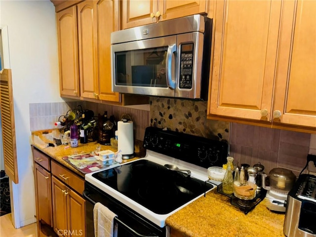 kitchen featuring light stone counters, range with electric cooktop, and tasteful backsplash