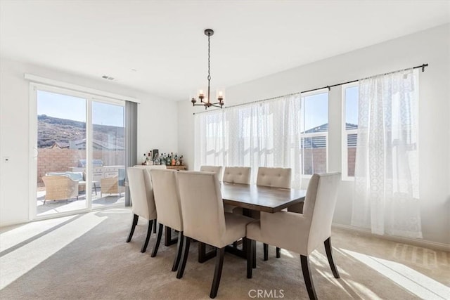 dining room with light carpet and a chandelier