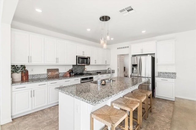 kitchen featuring white cabinets, appliances with stainless steel finishes, and an island with sink