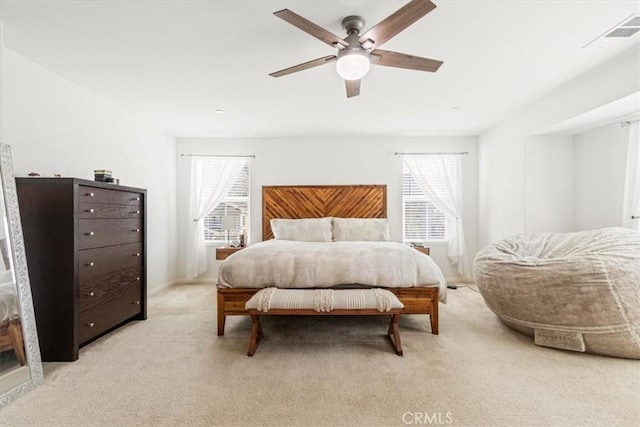 bedroom featuring ceiling fan, light colored carpet, and multiple windows