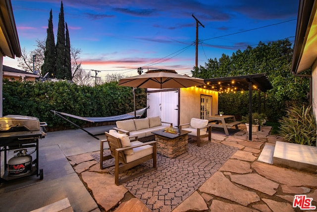 patio terrace at dusk with an outdoor living space with a fire pit and an outdoor structure