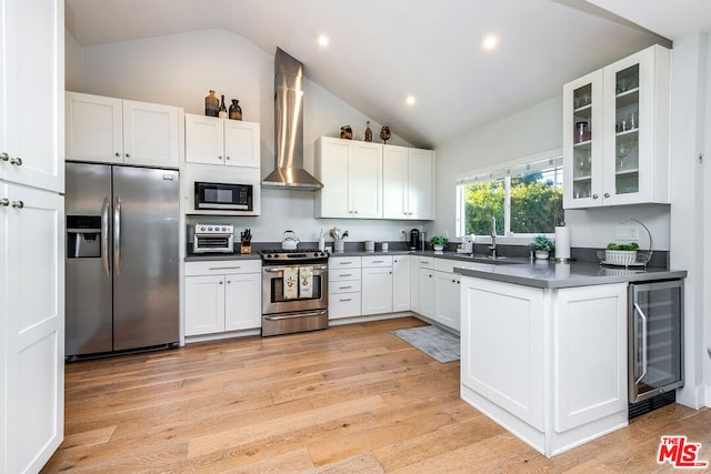 kitchen featuring wine cooler, lofted ceiling, stainless steel appliances, white cabinets, and wall chimney exhaust hood