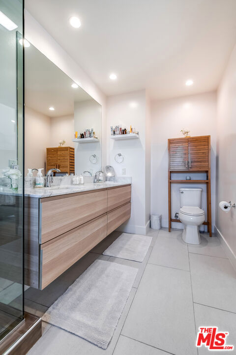 bathroom with toilet, vanity, tile patterned flooring, and a shower with door