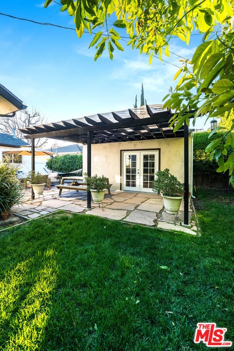 rear view of house featuring a pergola, a patio area, french doors, and a lawn