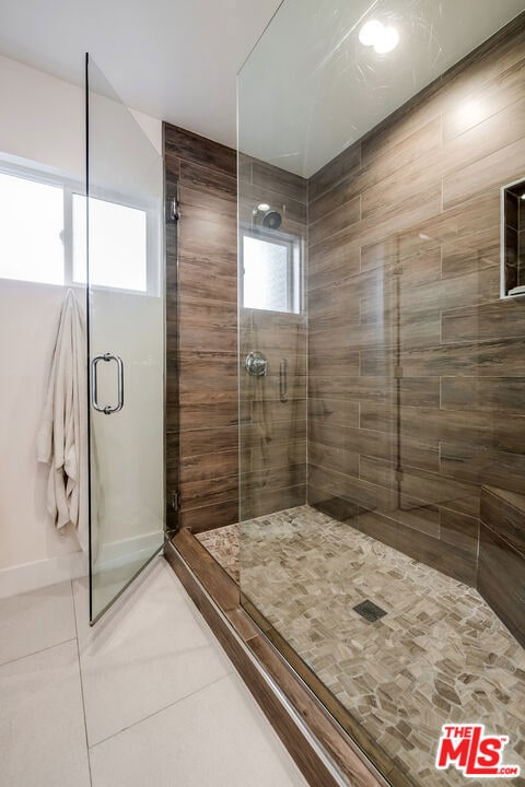 bathroom featuring a wealth of natural light, tile patterned flooring, and a shower with shower door