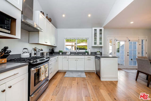 kitchen featuring white cabinetry, appliances with stainless steel finishes, french doors, wall chimney exhaust hood, and sink