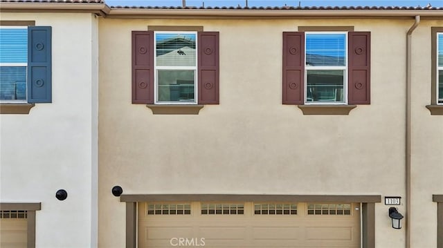 view of side of property featuring a tiled roof, an attached garage, and stucco siding