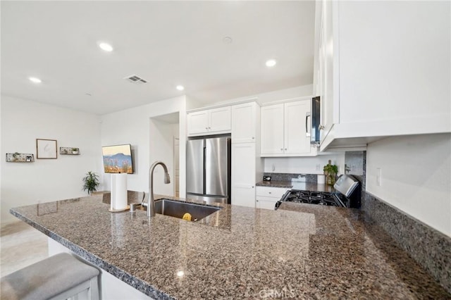 34495 Agave Dr Unit 1103, Winchester, CA 92596 - kitchen with stainless steel appliances, a sink, visible vents, white cabinetry, and dark stone counters