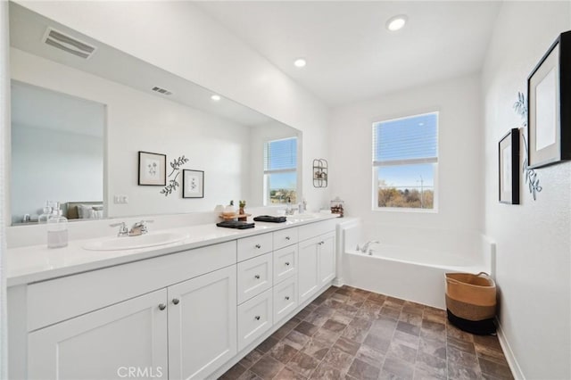 bathroom with vanity, a healthy amount of sunlight, and a tub to relax in