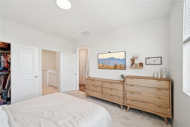 bedroom featuring a walk in closet, light colored carpet, and a closet