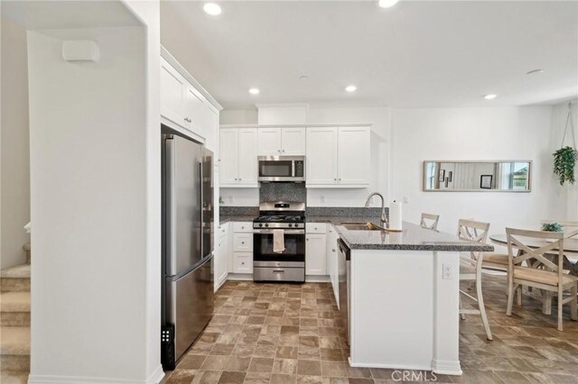 kitchen with stainless steel appliances, white cabinets, and a kitchen bar