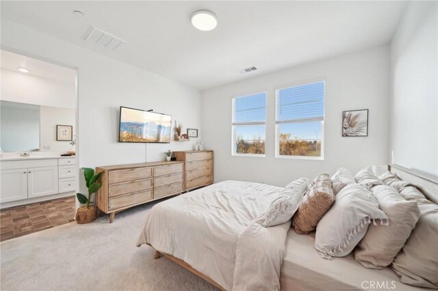 carpeted bedroom with sink and ensuite bathroom