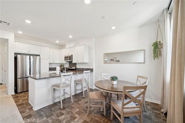 kitchen with white cabinetry, visible vents, appliances with stainless steel finishes, and dark stone countertops