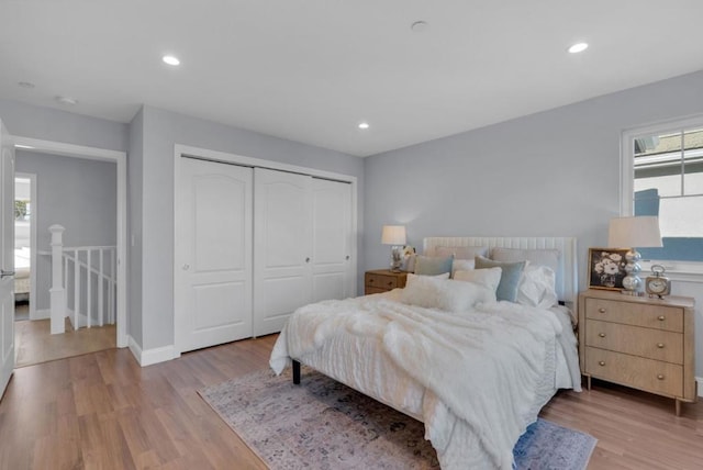 bedroom with a closet, light hardwood / wood-style floors, and multiple windows