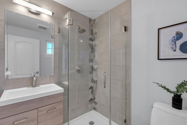 bathroom featuring toilet, a shower with door, and vanity