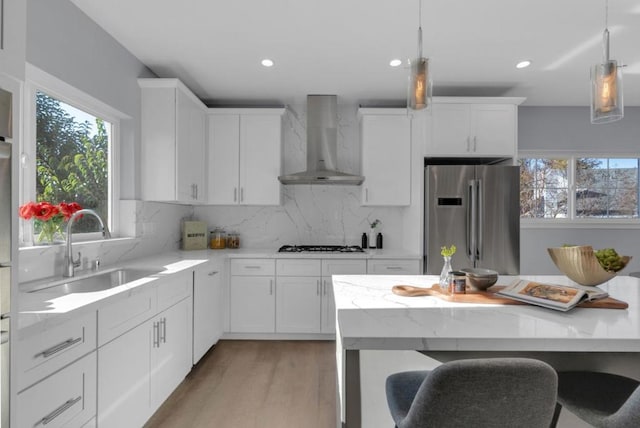 kitchen featuring white cabinets, backsplash, stainless steel refrigerator, and wall chimney exhaust hood