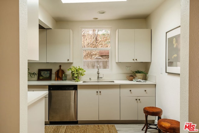 bar featuring sink, white cabinetry, dishwasher, and light wood-type flooring