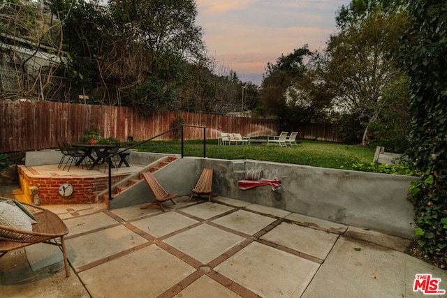 patio terrace at dusk with an outdoor fire pit and a yard