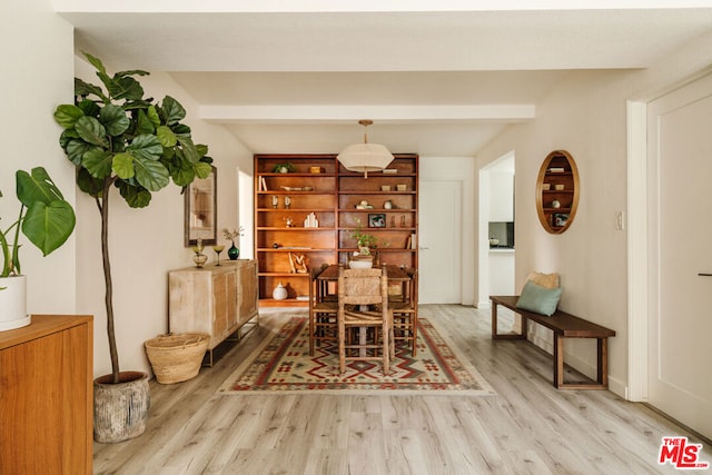 dining area with light wood-type flooring and beam ceiling