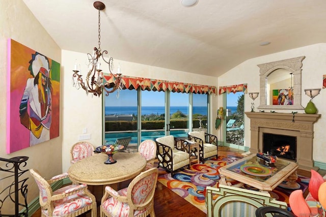 dining room featuring a chandelier, hardwood / wood-style floors, lofted ceiling, and a water view