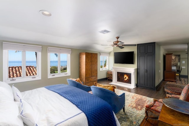 bedroom with ceiling fan, a water view, and dark hardwood / wood-style floors