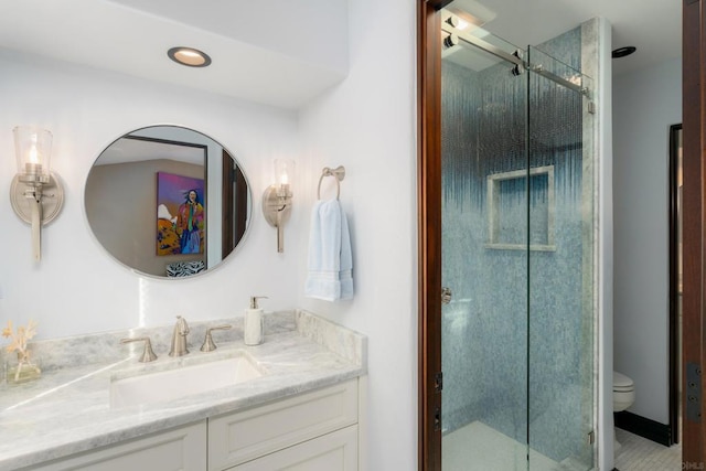 bathroom featuring toilet, a shower with shower door, and vanity