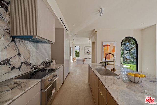 kitchen with light stone counters, sink, stainless steel electric range, and light hardwood / wood-style floors