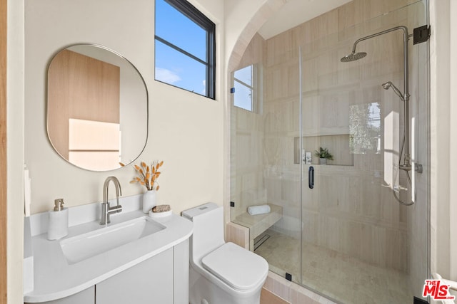 bathroom featuring vanity, a shower with shower door, and toilet