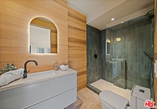 bathroom with tiled shower, vanity, toilet, and wood walls