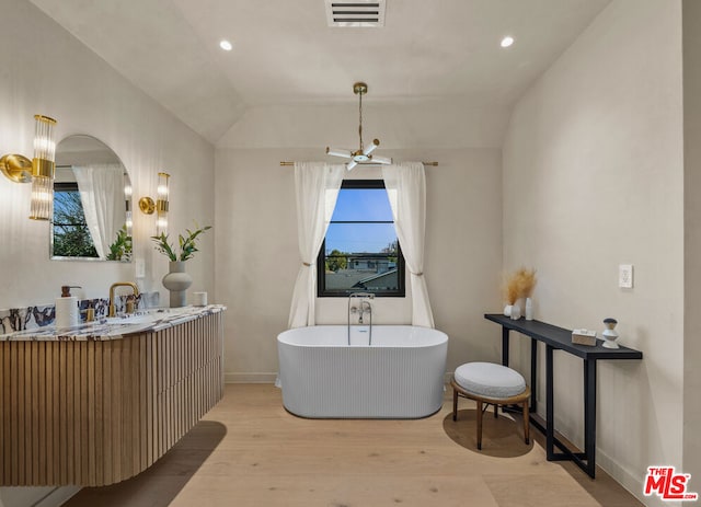 bathroom with a bathing tub, lofted ceiling, hardwood / wood-style flooring, vanity, and ceiling fan