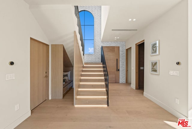 staircase with hardwood / wood-style flooring and brick wall