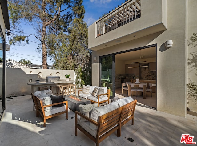 view of patio with an outdoor living space with a fire pit